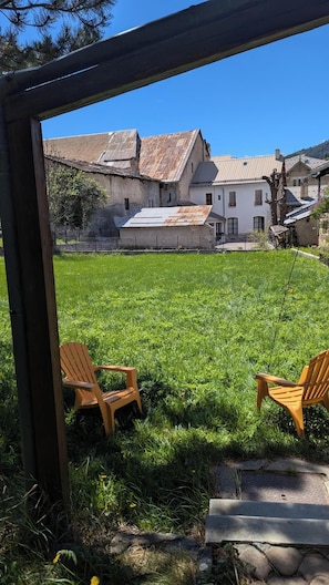 A grassy backyard with two wooden chairs, a stone pathway, and a metal fence.