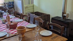 A dining area with a wooden table set for a meal, a vintage stove, and a window with curtains.