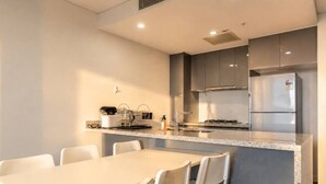 Eine moderne Küche mit Kochinsel, weißen Stühlen und einem Edelstahl-Kühlschrank.
