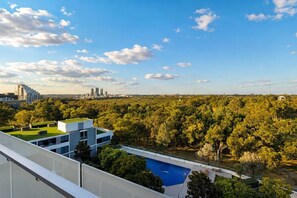 A modern building with a rooftop pool and a view of a city skyline. - Stylish 2BR Olympic Park | Pool, Gym & Parking (Sydney Olympic Park)