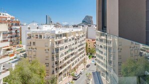 Ein Hochhaus mit mehreren Balkonen, freier Aussicht auf die Stadt und einer markanten Felsformation in der Ferne.