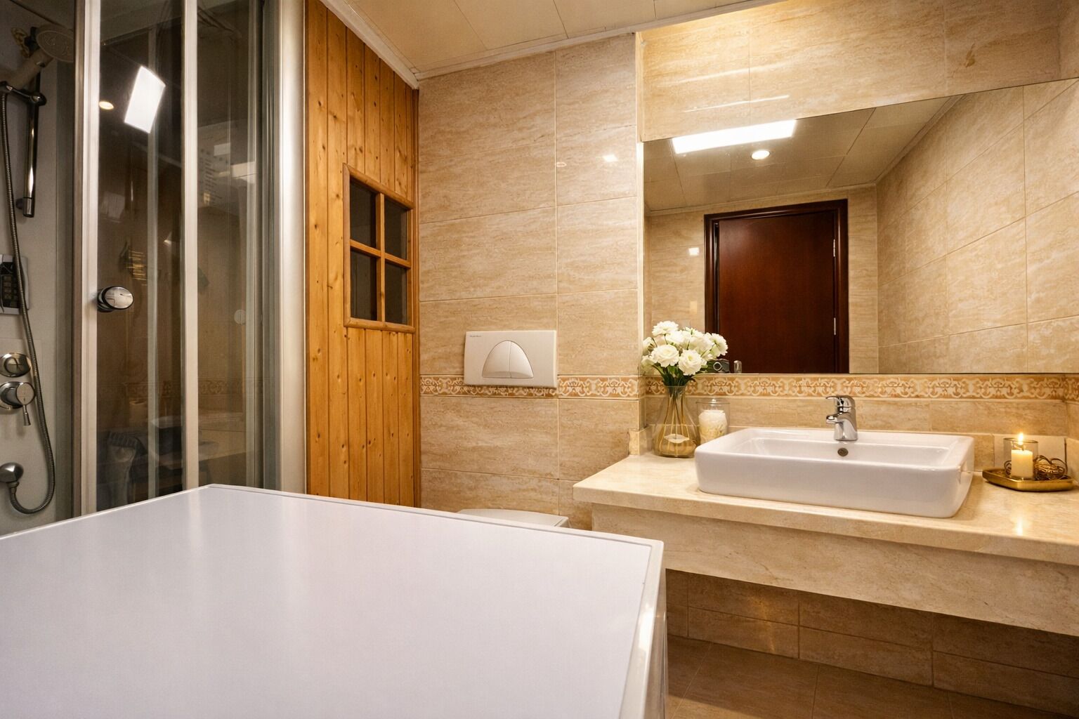 A bathroom with a shower, a sink, a mirror, and a wooden door.