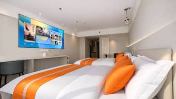 A modern hotel room with a large bed, a desk, and a television displaying a digital interface.