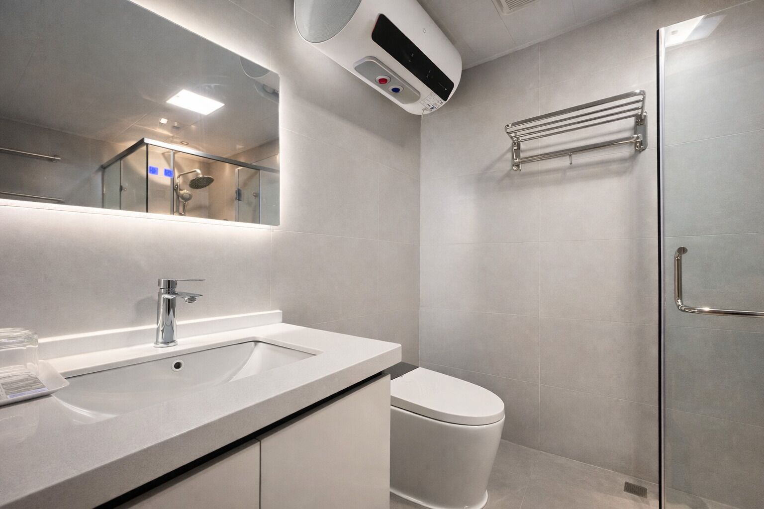 Un baño moderno con lavamanos, espejo, inodoro y zona de ducha.