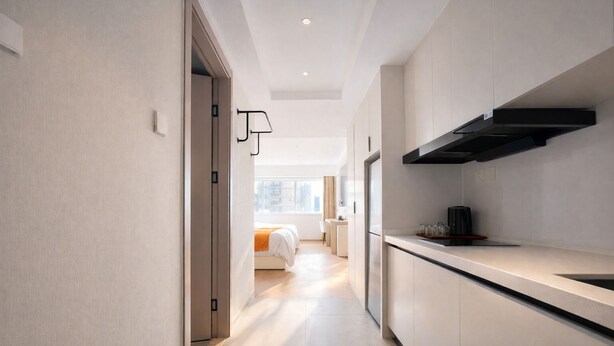 Une cuisine moderne dotée d’une cuisinière intégrée, un coin repas avec une table et des chaises, et une chambre à coucher avec un lit et une fenêtre.