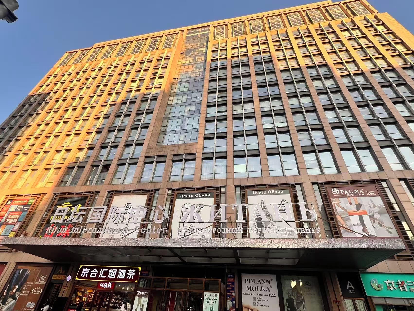 Un edificio de varios pisos con letreros comerciales en la planta baja, que incluyen una sala de cine y diversas tiendas.