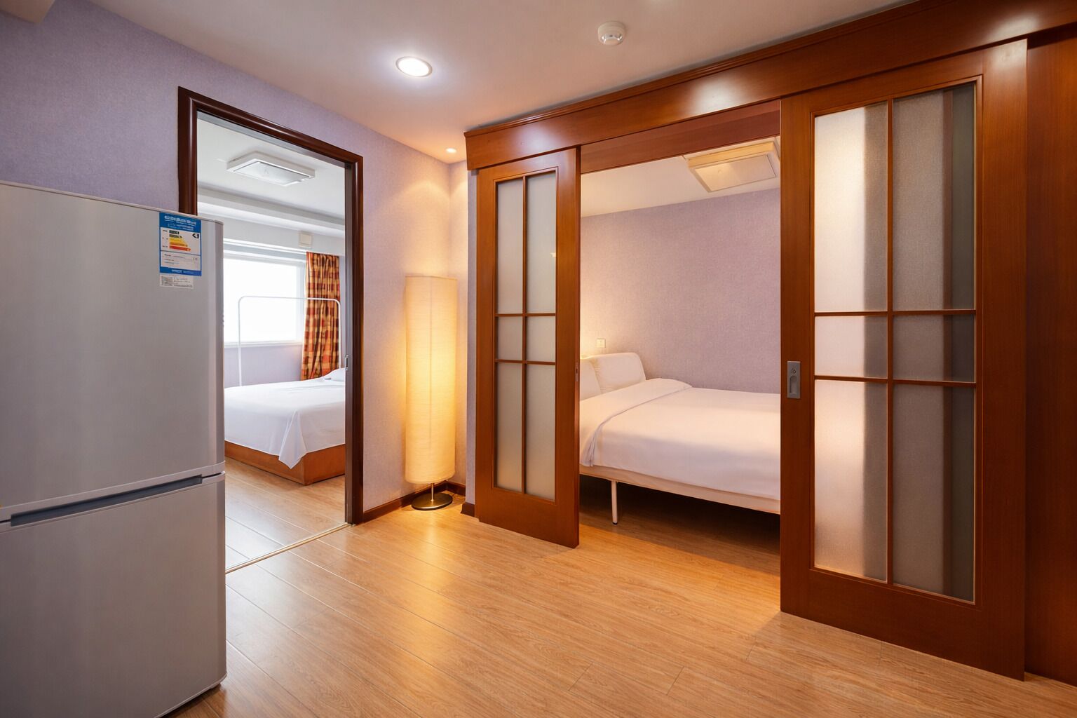 Une chambre d’hôtel comprenant un lit, une armoire, un réfrigérateur et une table de chevet.