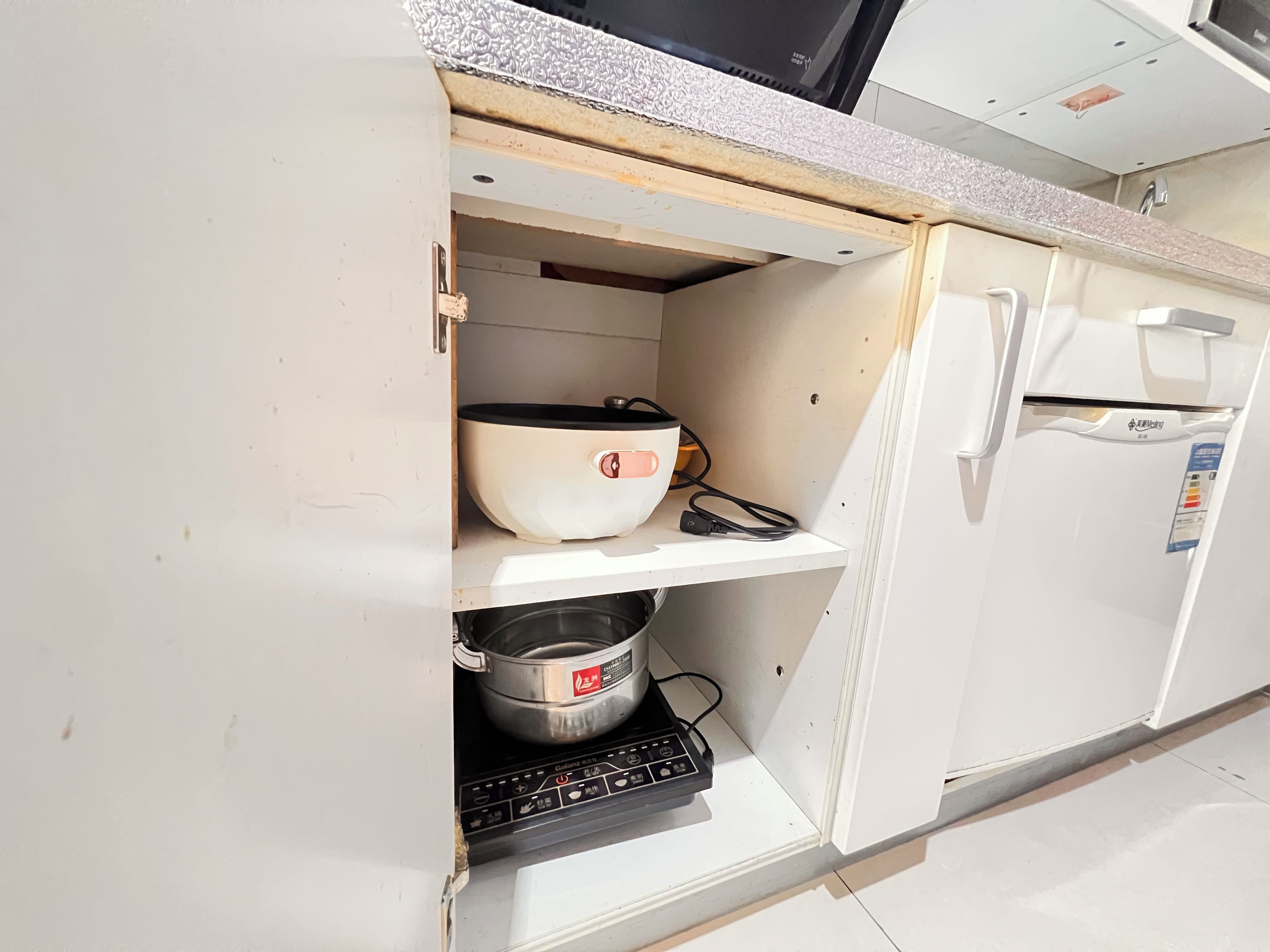 A kitchen with a microwave, a white bowl, a pot, and a black appliance on the counter.