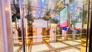 Vue intérieure d’un ascenseur doté de portes en verre, d’un écran numérique et d’un panneau indiquant le numéro de l’étage.