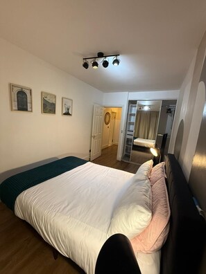 Ein Schlafzimmer mit einem Bett, einem Kleiderschrank, einem Spiegel und einer Tür zu einem Badezimmer.