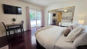 Ein Hotelzimmer mit Bett, Schreibtisch, Stuhl, Fernseher und einer Schiebetür zum Balkon.