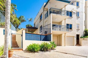 A multi-story residential building with balconies, a gated entrance, and a small garden area. - Eight, Villa Mar Colina (Yeppoon)