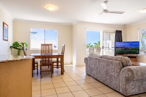 Ein Wohnzimmer mit Essbereich, einer Couch, einem Fernseher und einem Balkon mit Blick.