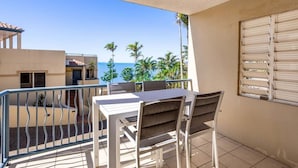 A balcony with a table and chairs, a view of the sea, and a building with a tiled floor. - Eight, Villa Mar Colina (Yeppoon)