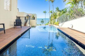 A swimming pool with a clear view of the ocean, a covered seating area, and a staircase leading to an upper level. - Eight, Villa Mar Colina (Yeppoon)