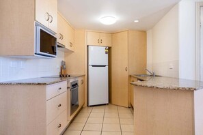 Eine kleine Küche mit Mikrowelle, Kühlschrank, Backofen und Spüle.