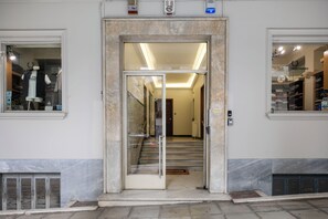 Ein Hotel Eingang mit Glastür, Treppe und Blick ins Innere.