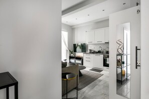 Eine moderne Küche mit weißen Schränken, einer schwarzen Arbeitsplatte und einer Essecke mit einer Couch und Stühlen.