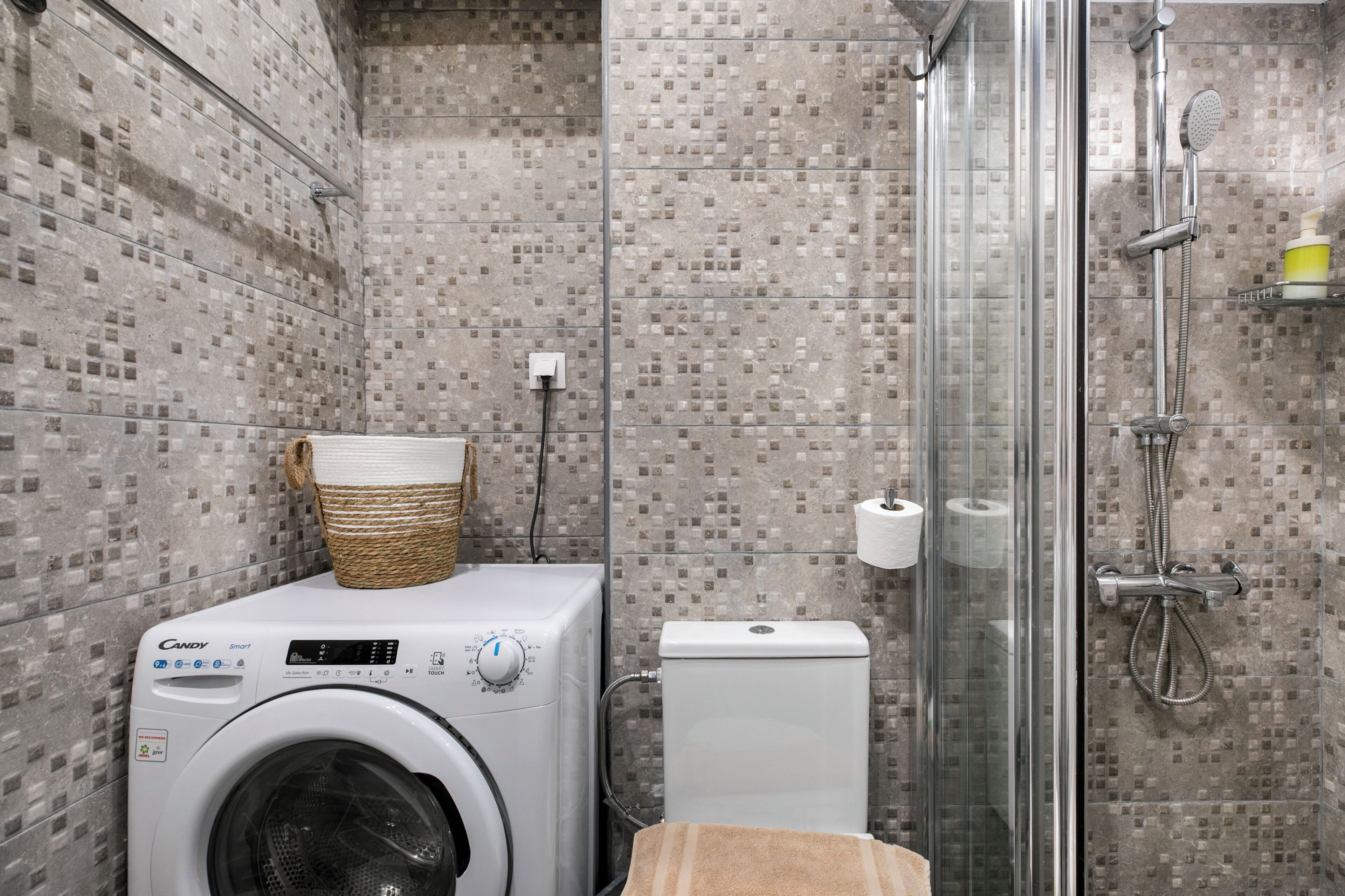 A bathroom with a washing machine, a toilet, and a glass-enclosed shower area.