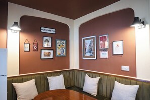 Um quarto com mesa de madeira, um banco estofado em verde e obras de arte emolduradas nas paredes.