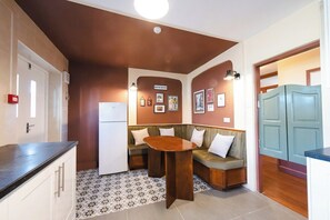A compact kitchen with a built-in refrigerator, a wooden bench with cushions, and a small table.