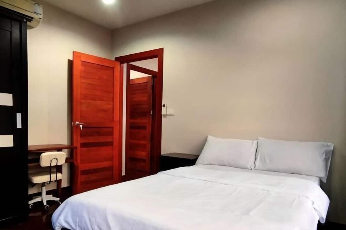 Ein Schlafzimmer mit einem Bett, einem Holzschrank und einem Schreibtisch mit Stuhl.