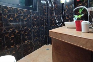 Un baño con pared de mármol, un lavabo, un espejo y una ducha.