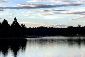 Un lago tranquilo con orilla arbolada y cielo despejado.