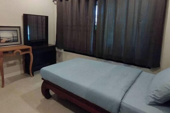 A room with a bed, a small table, a television, and a window with curtains.