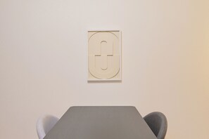 A minimalist room with a table and two chairs, a wall-mounted artwork, and a plain wall. - Imperial Azabu (Minato City)