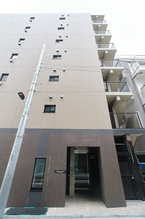 Un immeuble à plusieurs étages, doté d’une façade recouverte de carreaux, d’une entrée bien visible et d’un escalier menant à un niveau supérieur.