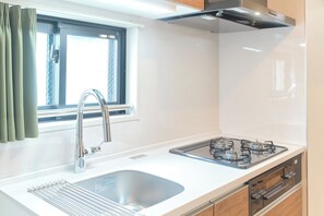 Una cocina moderna con un lavamanos de acero inoxidable, una estufa a gas y armarios de madera.