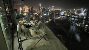 A high-rise balcony with a city view, a sofa, and a dining table. - Luxury 1 BR with Stunning Water Views (Dubai)