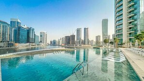 A swimming pool with a cityscape in the background. - Luxury 1 BR with Stunning Water Views (Dubai)