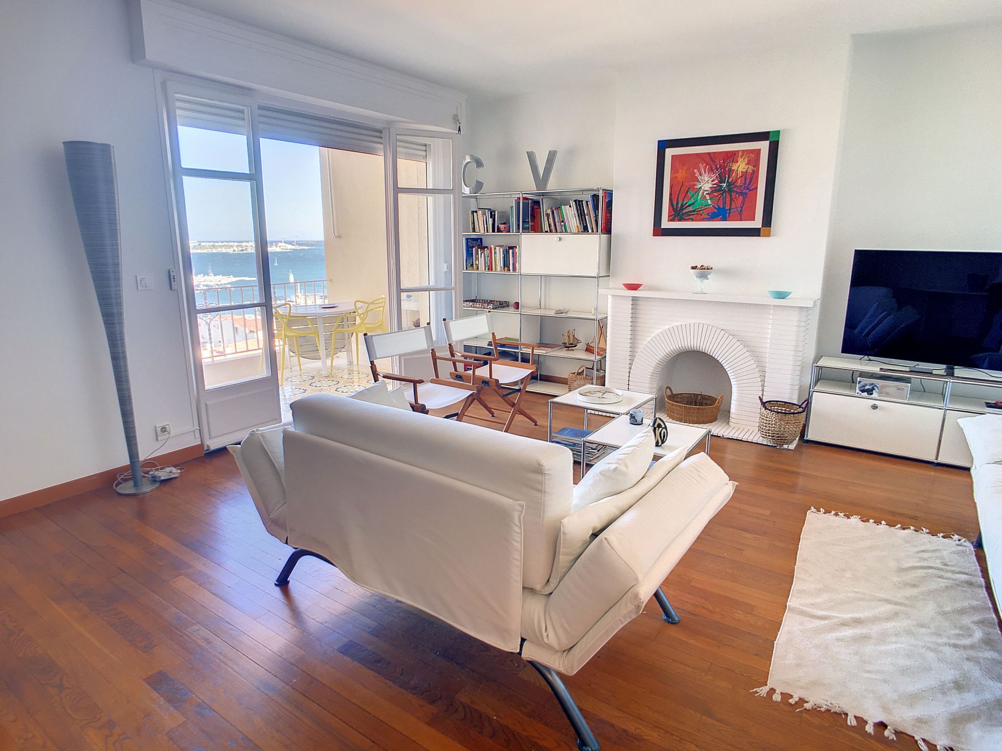 A living room with a white sofa, a fireplace, a bookshelf, and a television.