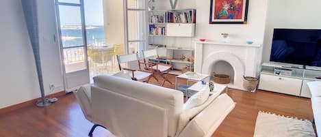 A living room with a white sofa, a fireplace, a bookshelf, and a television.