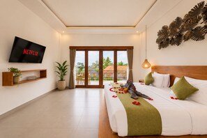 Habitación de hotel con cama, televisión, balcón y vistas al exterior.