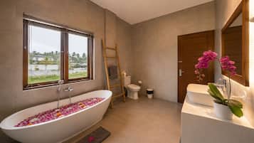 Un baño moderno con una bañera independiente, un inodoro y un lavamanos.