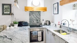 Een moderne keuken met een inbouwoven, een spoelbak en een marmeren aanrecht.