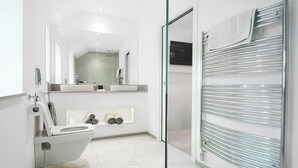 Een moderne badkamer met toilet, wastafel, spiegel en een douchecabine van glas.