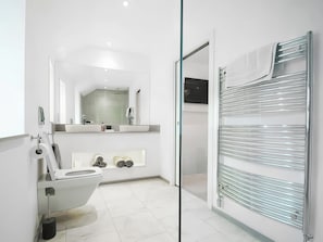 Ein modernes Badezimmer mit Toilette, Waschbecken, Spiegel und Duschkabine aus Glas.
