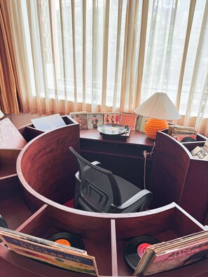 Een zithoek met een stoel, een lamp en vinylplaten op een tafel.