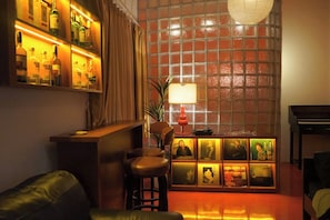 Een bar met flessen, een piano en ingelijste foto’s aan de muur.