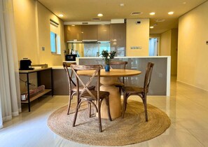 Une cuisine moderne avec une table ronde en bois et quatre chaises, un petit îlot central doté d’un évier et une fenêtre au-dessus du plan de travail.