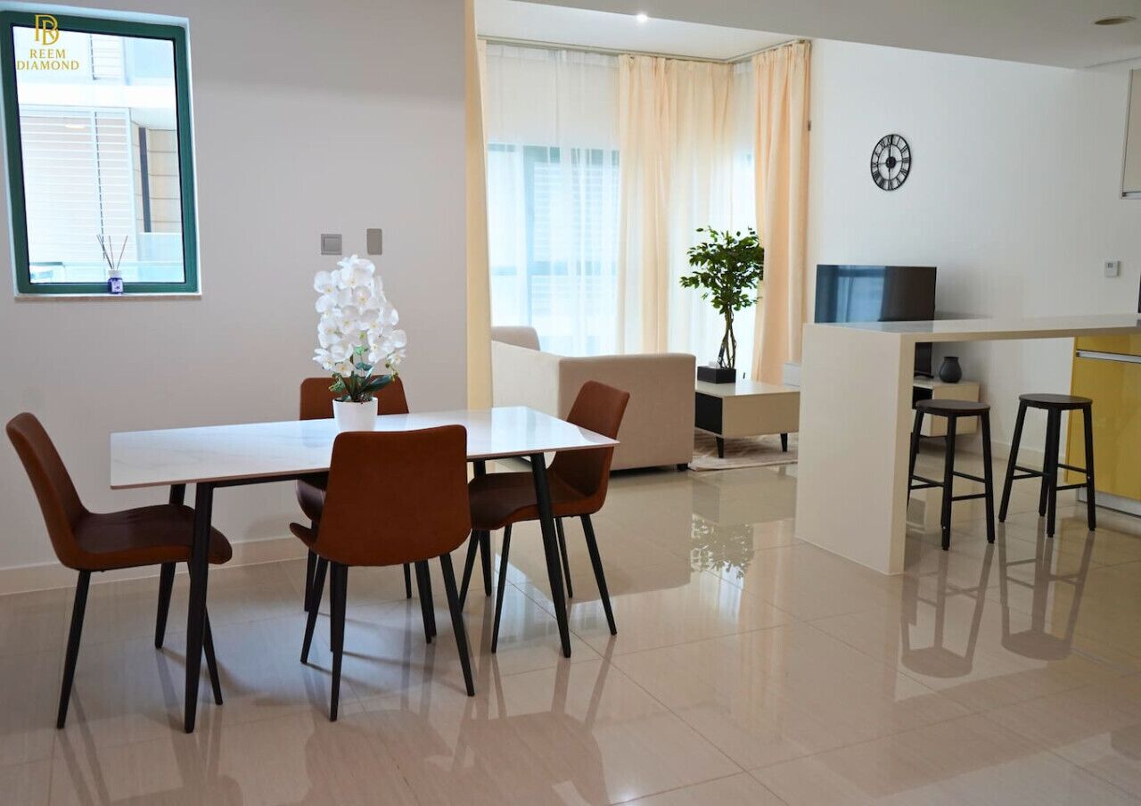 A modern living room with a dining table, chairs, a sofa, a TV, and a plant.
