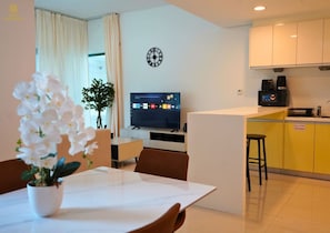 A modern hotel room with a dining area, a TV, a clock, and a kitchenette. - Spacious 1BR in the heart of Al Reem (Abu Dhabi)