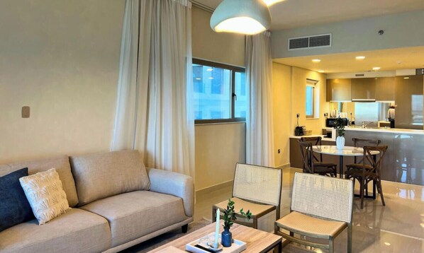Una sala de estar moderna con un sofá, sillas, una mesa de centro y un comedor con una mesa y sillas.