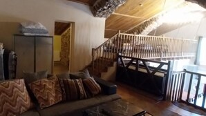 Ein gemütliches Wohnzimmer mit einer Couch, einem Schrank und einer Treppe, die in eine obere Ebene führt.