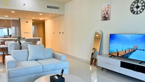 Ein modernes Wohnzimmer mit Sofa, Couchtisch, Fernseher und einem dekorativen Spiegel.