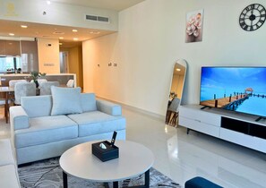 A modern living room with a sofa, coffee table, TV, and a decorative mirror. - Beachfront 2BR Escape in Al Reem (Abu Dhabi)